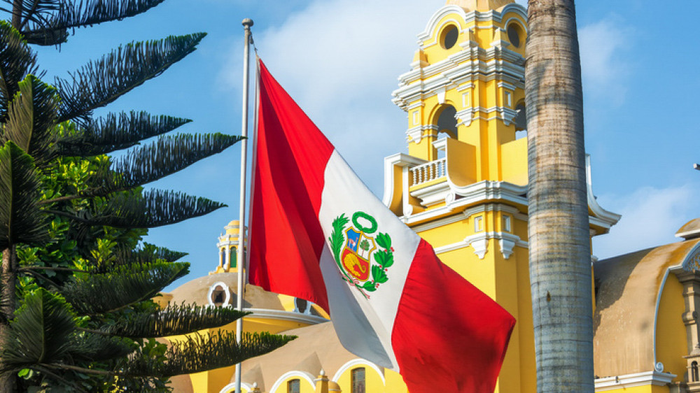 Die peruanische Flagge weht vor der gelben Kirche in Barranco ()